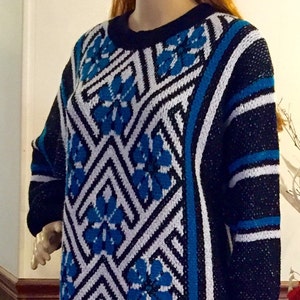 May include: A black and white sweater with a geometric pattern in blue. The sweater has a crew neck and long sleeves.