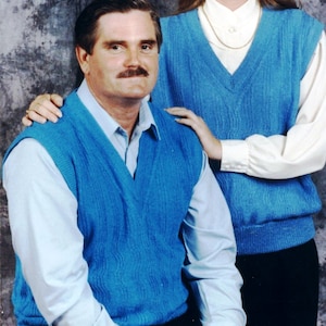 May include: Two people wearing blue knitted vests. The person on the left is wearing a white button-down shirt. The person on the right is wearing a white blouse.