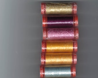 May include: A vertical stack of seven spools of sewing thread in various colors including gold, deep purple, magenta, orange, yellow, light blue, and pale yellow. Each spool features red plastic ends with the brand name Aurifil printed on them.