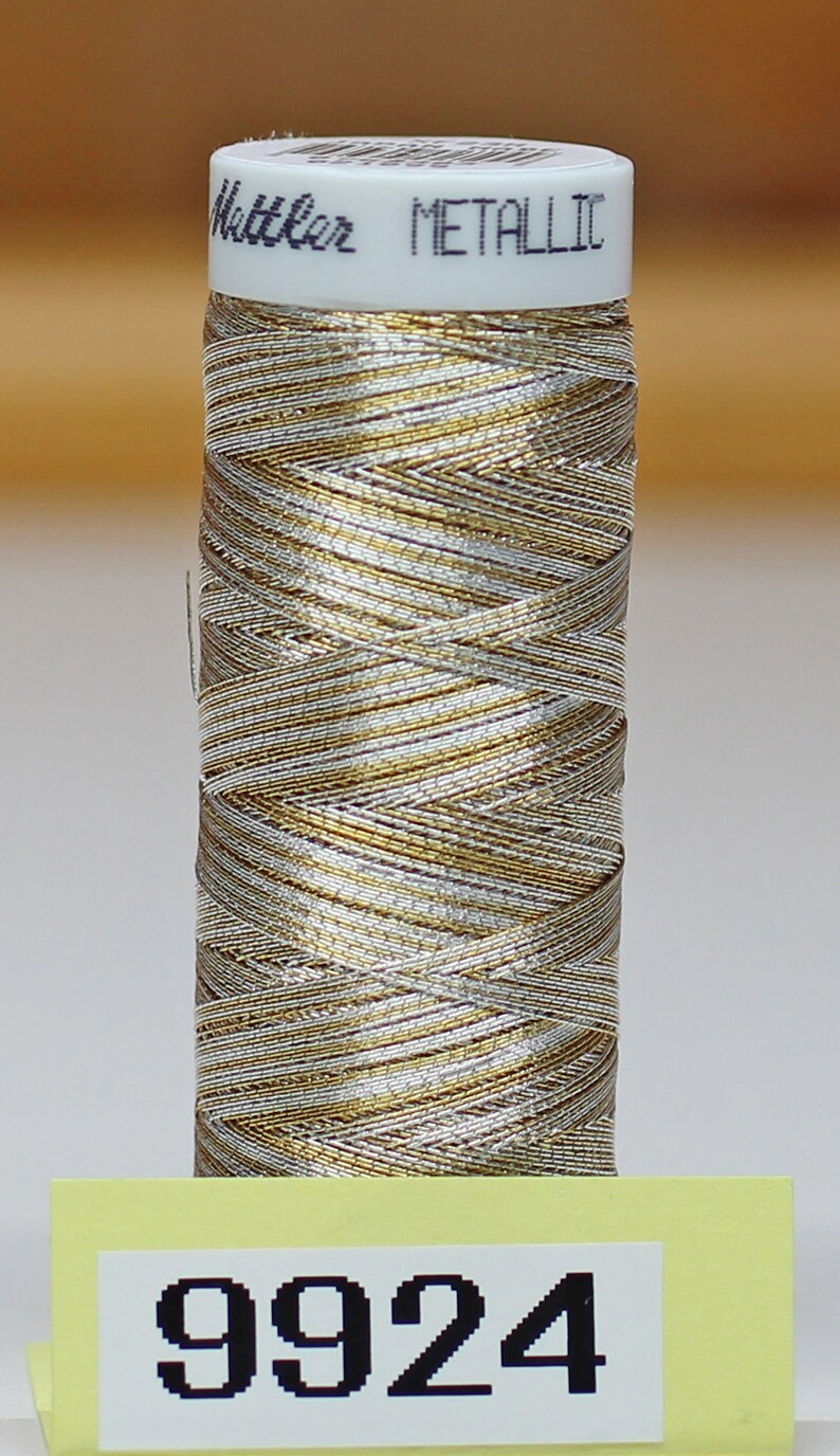 May include: A spool of gold and silver metallic thread with the text "Metallic" on the label. The number "9924" is printed on a yellow label.