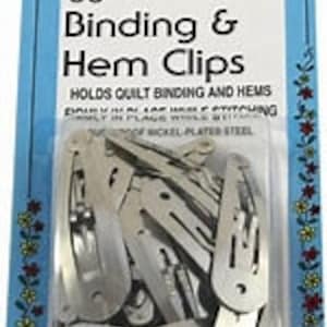 May include: A package of 30 silver binding and hem clips. The package is blue and white with the text "30 Binding & Hem Clips" and "HOLDS QUILT BINDING AND HEMS FIRMLY IN PLACE WHILE STITCHING".