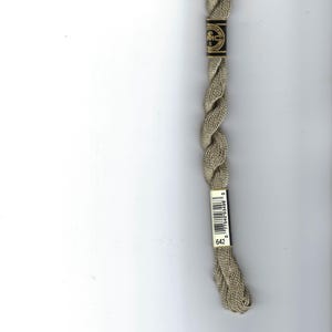 May include: A skein of light beige embroidery thread with a twisted texture. The thread features a black and gold label at the top marked DMC 5 and a white label at the bottom with a barcode and the number 642 printed in black ink.