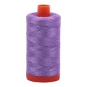 Puede incluir: Una bobina de hilo morado con una bobina de pl&aacute;stico roja.
