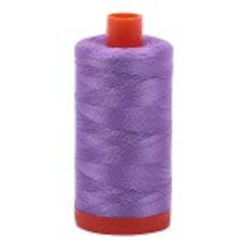 Puede incluir: Una bobina de hilo morado con una bobina de pl&aacute;stico roja.