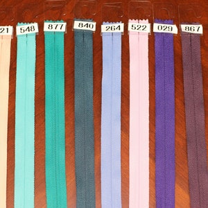 May include: A close-up of ten different colors of zipper tape, each labeled with a number. The colors are: yellow, peach, light blue, teal, dark blue, light blue, pink, purple, brown, and dark blue.