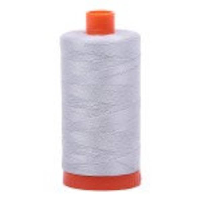 Puede incluir: Una bobina de hilo gris plateado con una bobina de pl&aacute;stico naranja.