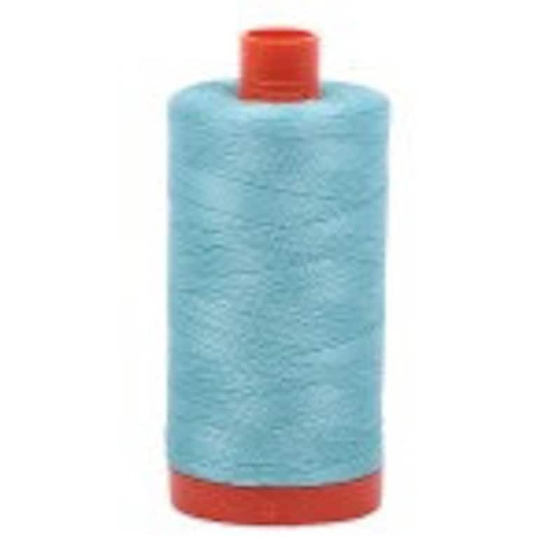 Puede incluir: Una bobina de hilo azul claro con una bobina de pl&aacute;stico roja.