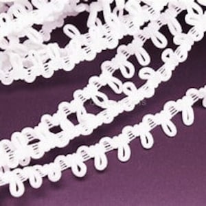 May include: White elastic trim with a decorative looped pattern. The trim has a delicate, lacy look and is perfect for adding a touch of elegance to any project.