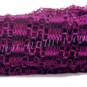 May include: A close-up of a purple and black crocheted trim with a ruffled edge. The trim is made of a soft, textured yarn.