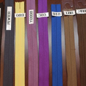 Puede incluir: Una selecci&oacute;n de diez cintas de cremallera en varios colores, incluyendo negro, carb&oacute;n, peltre, amarillo, morado, azul, marr&oacute;n y marr&oacute;n oscuro. Las cintas de cremallera est&aacute;n etiquetadas con sus c&oacute;digos de color correspondientes: BK, CHARCOAL, PEWTER, 089, Y0998, 303, 918, LBR, MBR y DBR.