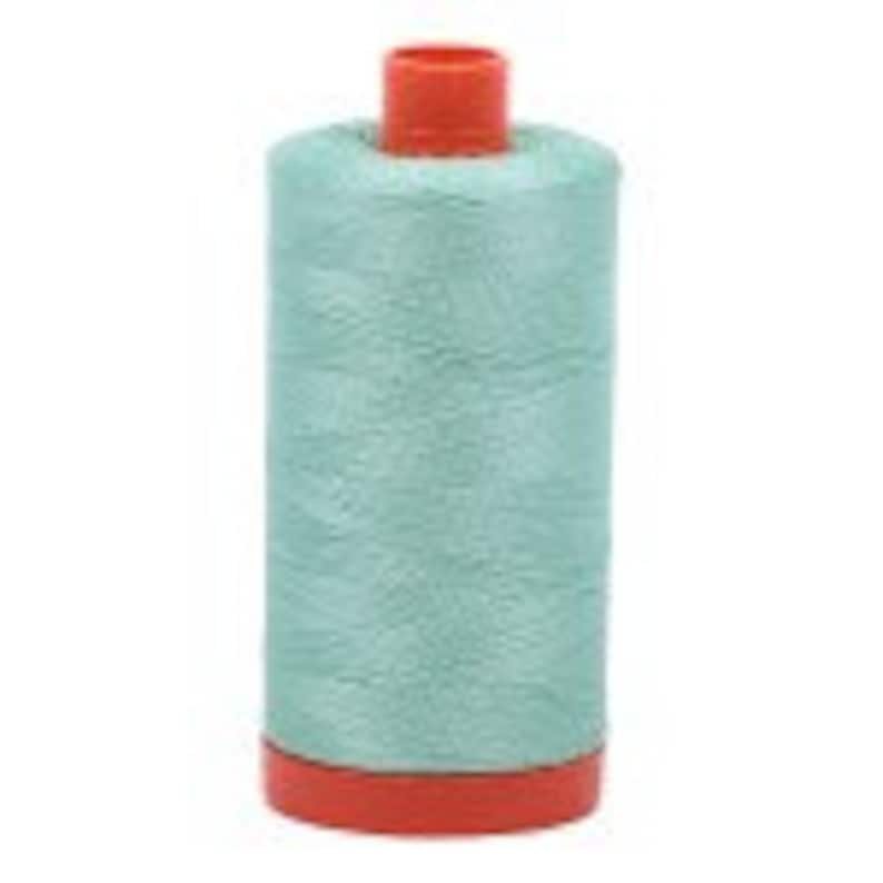 Puede incluir: Una bobina de hilo azul claro con una bobina de pl&aacute;stico naranja.