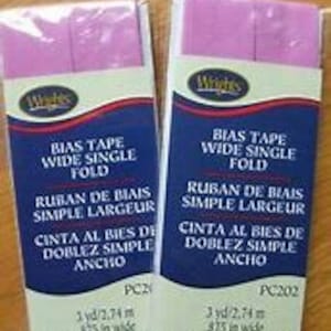 May include: Two packages of pink bias tape, each containing 3 yards of 8/75 inch wide single fold bias tape. The packages are labeled "Bias Tape Wide Single Fold" in English, French, and Spanish.