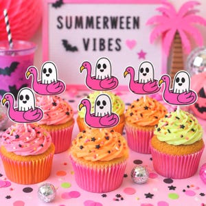 May include: A collection of cupcakes topped with white ghost figures sitting in pink flamingo pool floats. The cupcakes feature pink, orange, and light green frosting with colorful sprinkles. A sign in the background reads SUMMERWEEN VIBES.