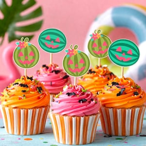 May include: Six cupcakes with orange and pink frosting, decorated with sprinkles and watermelon-themed toppers. The cupcakes sit in striped paper cups, creating a festive and colorful display. A pink background and a blue surface complete the scene.