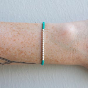 May include: A turquoise string bracelet with silver beads.