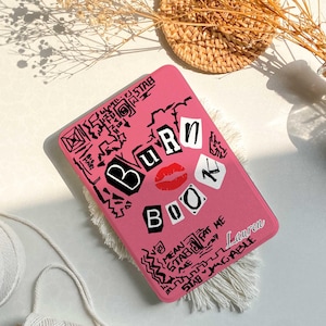 May include: Pink laptop case with a black and white design that says "Burn Book" with a red lipstick kiss mark. The case has a personalized name "Lauren" on it.