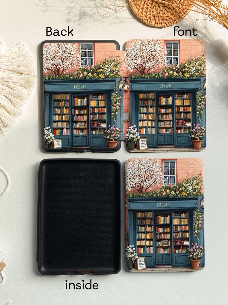 Op de afbeelding: Een zwarte Kindle Paperwhite hoes met een bloemenontwerp met een boekwinkel met de tekst "Book Shop". De hoes heeft een roze bakstenen buitenkant met een blauwe deur en een blauw raam. De hoes is open om een zwart interieur te onthullen.
