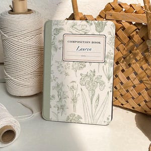 Puede incluir: Un cuaderno de composición verde con un patrón floral y el texto "COMPOSITION BOOK" y "Lauren" en la portada.