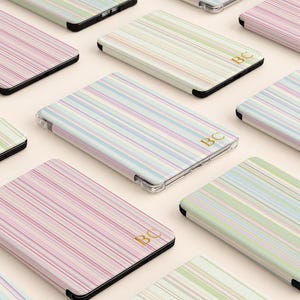 May include: A collection of rectangular cases featuring vertical stripes in pastel shades of pink, green, blue, and yellow. Some cases are personalized with the gold embossed letters BC, while others remain plain. Each case has a black border.