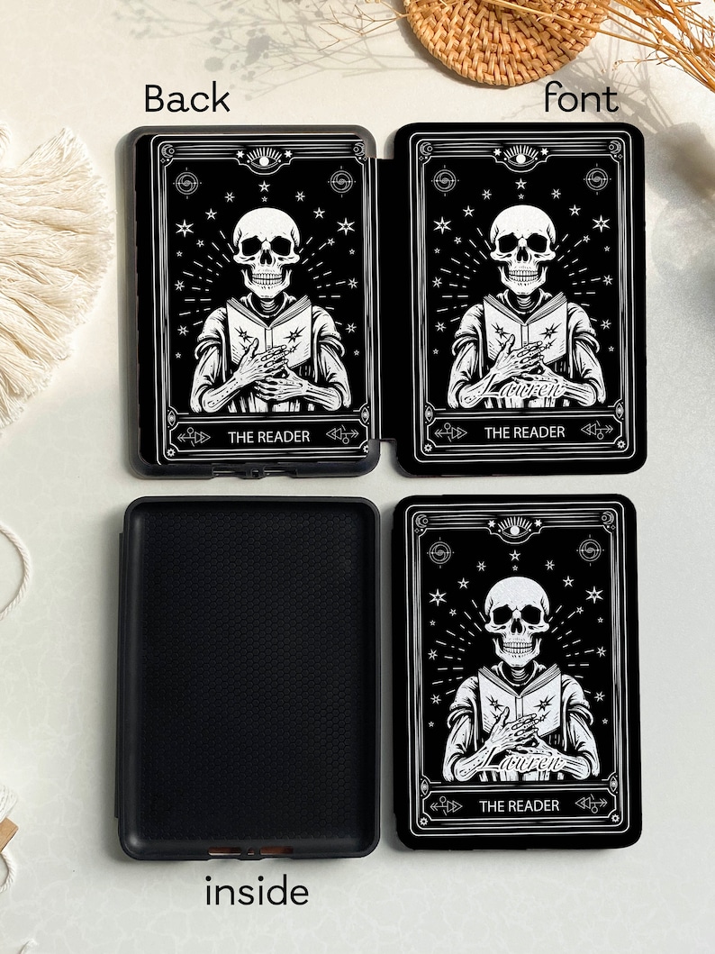 May include: Black and white tarot card design featuring a skeleton reading a book. The card is titled "The Reader" and is surrounded by stars. The card is on a black background.
