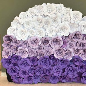 May include: A large, semi-circular display of paper roses in shades of white, lavender, and purple. The roses are arranged in a gradient, transitioning from white at the top to deep purple at the bottom. A banner on the left side reads "Project Cuffway".