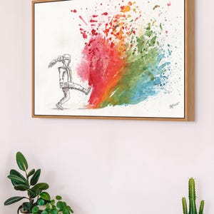 May include: A framed watercolor print depicts a figure kicking a vibrant explosion of color. The artwork features a person in grayscale kicking into a burst of red, orange, green, and blue hues. The artwork is in a wooden frame.