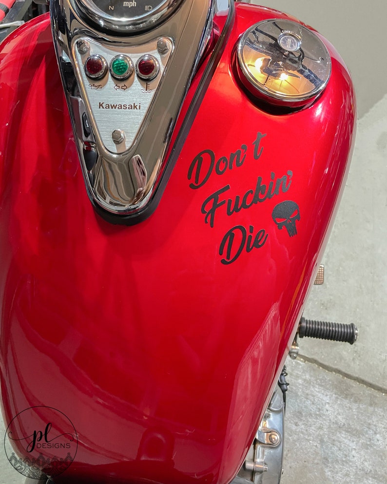 May include: A red motorcycle gas tank with the text "Don't Fuckin' Die" and a skull graphic. The tank also features a Kawasaki emblem and gauges.