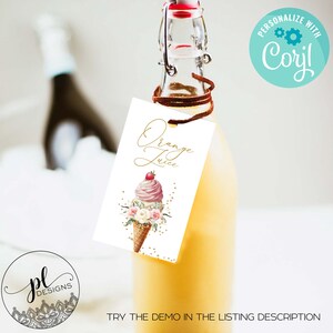 May include: A clear glass bottle filled with orange juice, featuring a tag that reads "Orange Juice" in elegant script. The tag showcases an ice cream cone design with pink ice cream, a cherry, and floral accents.