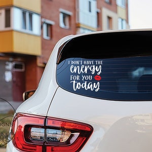 May include: White car rear window decal with the text "I don't have the energy for you today" in a script font, with a red lip graphic. The decal is applied to the car's rear window.