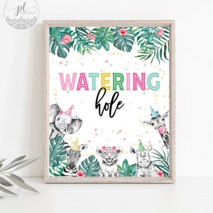 May include: A framed print with the words "WATERING hole" in colorful letters. The print features watercolor illustrations of an elephant, zebra, lion, rhino, and giraffe, each wearing a party hat. Tropical leaves and flowers surround the text.