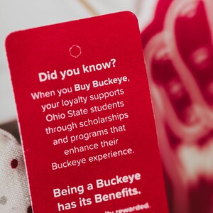May include: A red card with white text that reads "Did you know? When you Buy Buckeye, your loyalty supports Ohio State students through scholarships and programmes that enhance their Buckeye experience. Being a Buckeye has its Benefits. Have your loyalty rewarded. Scan below for exclusive offers and chances to win rewards from the official loyalty programme."