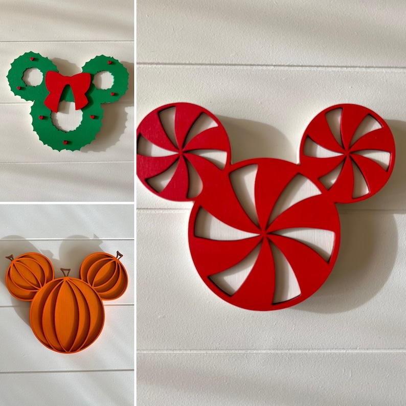 May include: Three wooden Christmas ornaments in the shape of Mickey Mouse's head. The first ornament is green with red holly and a red bow. The second ornament is red with a white peppermint swirl design. The third ornament is orange and resembles a pumpkin.