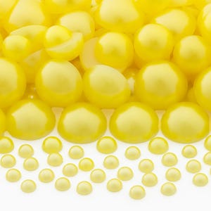 May include: A collection of numerous bright yellow, smooth, half-round beads of varying sizes. The beads have a glossy, reflective finish and a flat bottom, arranged in a dense cluster at the top that transitions into a scattered pattern below.