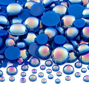 May include: A large assortment of iridescent blue and solid blue round cabochons. The cabochons are of various sizes and are arranged in a random pattern.