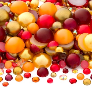 May include: A vibrant assortment of decorative beads and gems in various sizes and shapes. The color palette includes shades of red, orange, gold, and burgundy. Some beads are spherical, while others are faceted or cut in half.