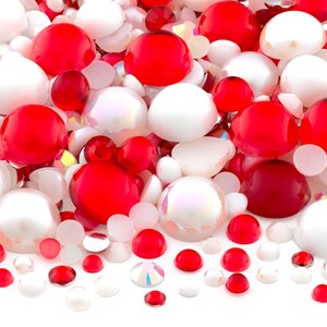 May include: A collection of red and white round beads, some with iridescent finishes. The beads are various sizes and are scattered on a white background.