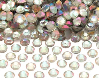 May include: A large pile of iridescent clear rhinestones, with a smaller group of rhinestones spread out below.