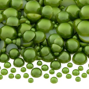 May include: A large assortment of green, round, flat-backed cabochons in various sizes. The cabochons are arranged in a pile with smaller cabochons scattered in front.