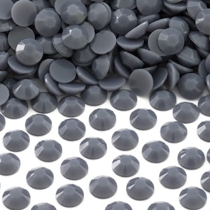 May include: A pile of gray, round, flat-backed rhinestones. The rhinestones are arranged in a grid pattern on a white background.