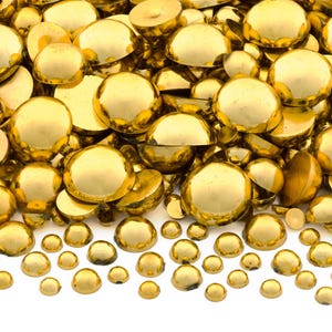 May include: A large pile of gold-colored round cabochons, with a smaller row of cabochons in the foreground. The cabochons are smooth and shiny.