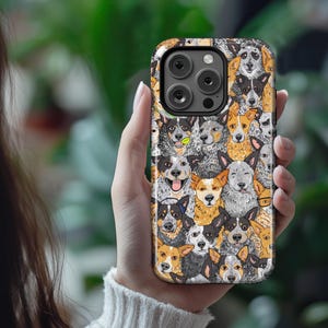 May include: A black phone case with a colorful pattern of Australian Shepherd dogs. The case has a camera lens cutout and a raised lip around the edges.