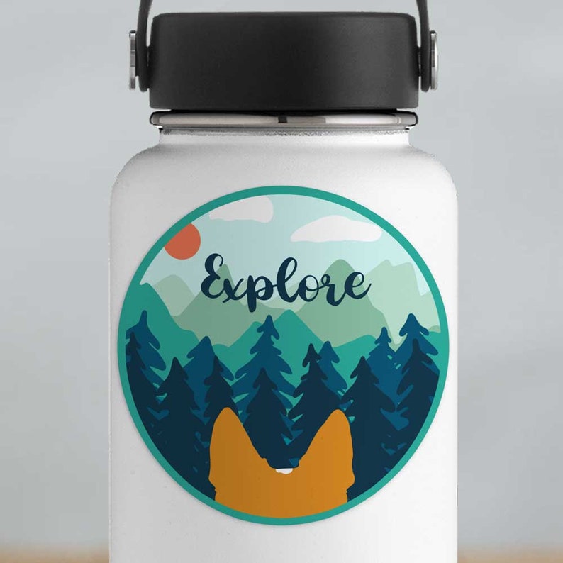 May include: A round sticker with a mountain landscape and the word "Explore" in a cursive font. The sticker is on a white water bottle. The mountains are blue and green, and the sky is blue with white clouds. There is a red sun in the upper left corner of the sticker.