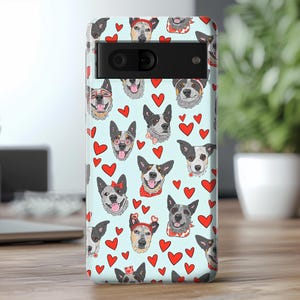 May include: A blue phone case with a pattern of Australian Shepherd dogs and red hearts. The case has a cutout for the camera lens.