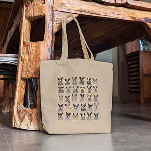 May include: A beige canvas tote bag with a pattern of 36 Australian Shepherd dogs in various poses. The dogs are all different colors and have different expressions.