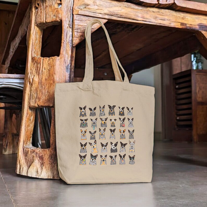 May include: A beige canvas tote bag with a pattern of 36 Australian Shepherd dogs in various poses. The dogs are all different colors and have different expressions.