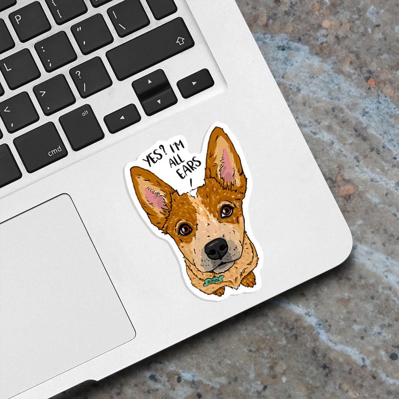 May include: A sticker featuring a cartoon illustration of a red and white Australian Cattle Dog with big ears and the text "YES? I'M ALL EARS!"