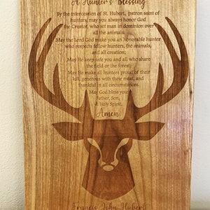 May include: A wooden plaque with a deer silhouette and a hunter's blessing engraved in the wood. The text reads: "A Hunter's Blessing By the intercession of St. Hubert, patron saint of hunters, may you always honor God the Creator, who set man in dominion over all the animals. May the Lord God make you an honorable hunter who respects fellow hunters, the animals, and all creation; May He keep safe you and all who share the field or the forest; May He make all hunters proud of their kill, generous with their meat, and thankful in all circumstances. May God bless you: Father, Son, & Holy Spirit. Amen. Francis John Hubert April 19th. 2021"