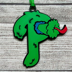 May include: Green, red, and blue Christmas ornament shaped like a monster with a tongue sticking out.