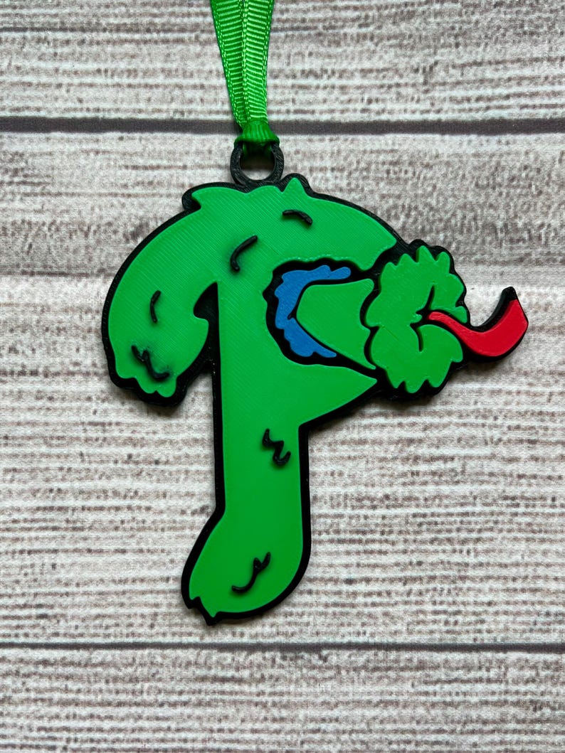 May include: Green, red, and blue Christmas ornament shaped like a monster with a tongue sticking out.