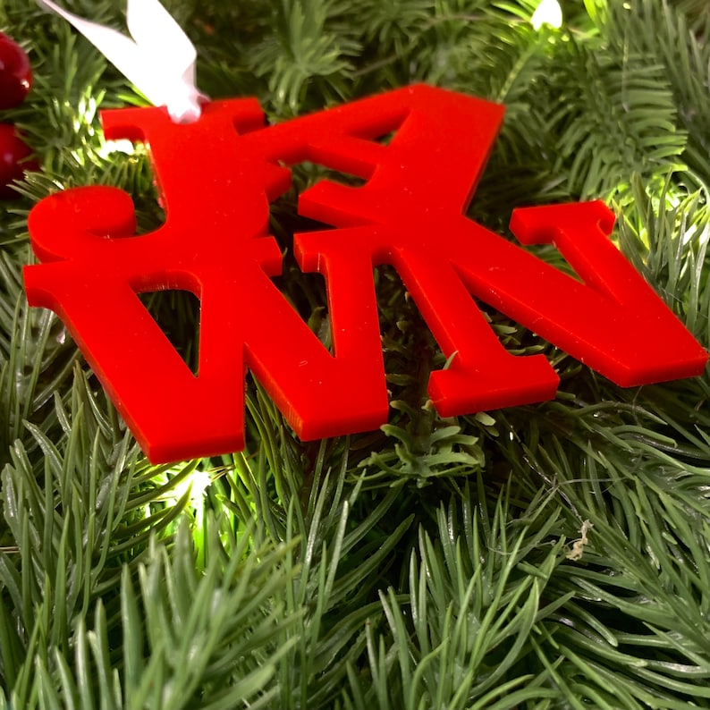 Op de afbeelding: Rode kerstversiering met het woord "WIN" in dikke, blokletters.